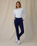 Midday Long Sleeve Polo in White, full length front view on model with hands in pockets showing a fitted collared long sleeve polo with a half-button neckline, paired with navy pants and white golf shoes