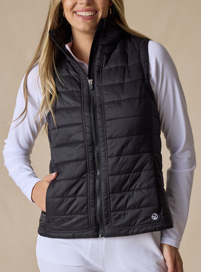 Cloud Vest in Black, front view on model featuring a black quilted full-zip vest with mock neck collar and front pockets with hand inserted styled with a white long sleeve top and white pants