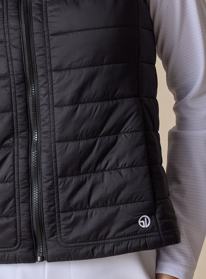 Cloud Vest in Black, close-up front view on model featuring the horizontal quilted pattern, tonal zipper, and Straight Down embroidered logo at the hem