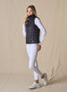 Cloud Vest in Black, side view on model featuring a black quilted full-zip vest with mock neck collar and Straight Down logo at the hem styled with a white long sleeve top, white pants, and white shoes