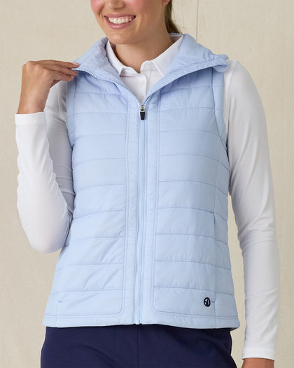 Cloud Vest in Powder, front view on model featuring a light blue quilted full-zip vest with mock neck collar being held open styled with a white long sleeve top and navy pants