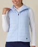 Cloud Vest in Powder, front view on model featuring a light blue quilted full-zip vest with mock neck collar being held open styled with a white long sleeve top and navy pants