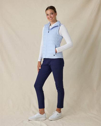 Cloud Vest in Powder, full length side view on model featuring a light blue quilted full-zip vest with mock neck collar and tonal logo detail styled with a white long sleeve top, navy pants, and white shoes