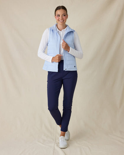 Cloud Vest in Powder, full length front view on model featuring a light blue quilted full-zip vest being held open to show the interior styled with a white long sleeve top, navy pants, and white shoes