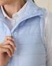 Cloud Vest in Powder, close-up front view on model featuring the mock neck collar, horizontal quilted pattern, and silver zipper pull detail styled with a white collared shirt