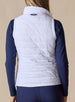Cloud Vest in White, back view on model featuring a white quilted vest with Straight Down embroidered logo at the center back neck styled with a navy long sleeve top and navy pants