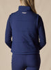 Women's Sandy Vest in New Indigo, back view on model featuring the Straight Down logo embroidered at center back on a navy quilted puffer vest, layered over a navy long sleeve top, paired with navy pants