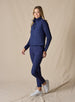 Women's Sandy Vest in New Indigo, full length side view on model featuring a navy quilted puffer vest layered over a navy long sleeve top, paired with navy pants and white golf shoes