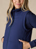 Women's Sandy Vest in New Indigo, close-up front detail featuring the full zip closure and high neck on a navy quilted puffer vest layered over a navy long sleeve top