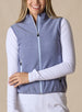 Lucia Vest in Bluestone, front view on model featuring a blue-violet fleece full-zip vest with mock neck collar and light blue contrast zipper styled with a white long sleeve top and white pants