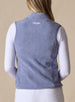 Lucia Vest in Bluestone, back view on model featuring a blue-violet fleece vest with embroidered logo detail at the center back neck styled with a white long sleeve top and white pants
