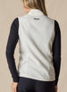 Lucia Vest in Cream, back view on model featuring an ivory fleece vest with embroidered logo detail at the center back neck styled with a black long sleeve top and black pants