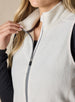 Lucia Vest in Cream, close-up front view on model featuring the mock neck collar being pulled open to show the grey contrast zipper tape and fleece lining detail