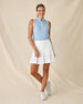 Women's Georgia Stripe Sleeveless Polo in Coastal, full length model view featuring a light blue and white pinstripe sleeveless polo with a gathered stand collar and white contrast armhole trim, styled with a white pleated skort and white shoes