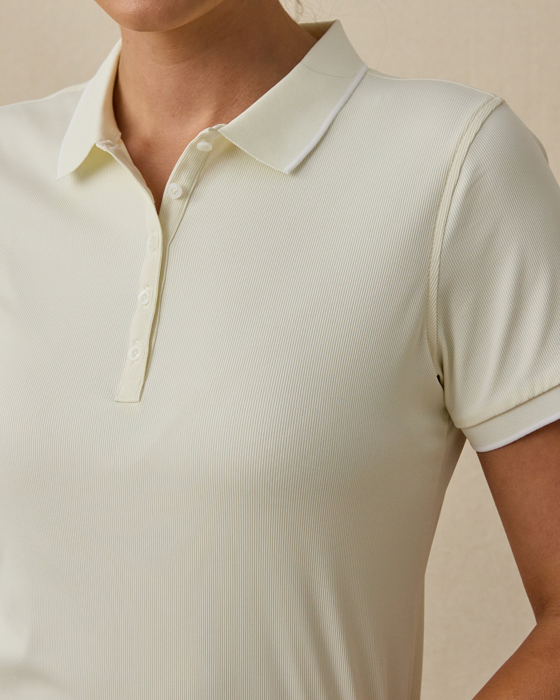 Close-up of the Sindy Rib Knit Polo in Coconut highlighting the fine ribbed texture, button placket, collar, and contrast sleeve trim.