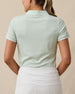 Back view of a woman wearing the Sindy Polo in Lemongrass with a white skort.