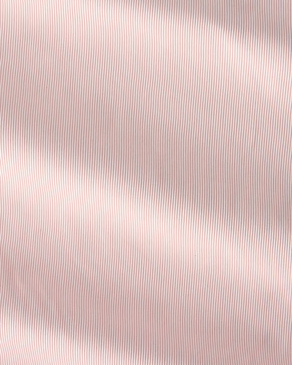 A close-up of a light blush pink fabric with a fine vertical ribbed texture and soft, diagonal folds.