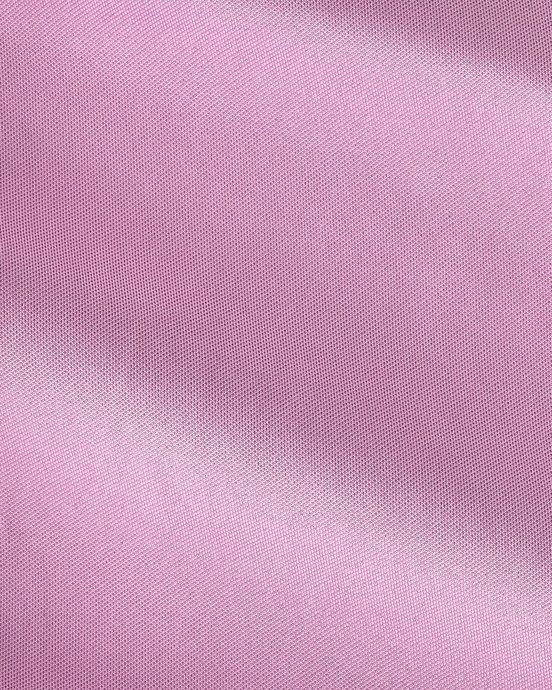 A close-up of light pink fabric with a fine woven texture and soft diagonal folds.