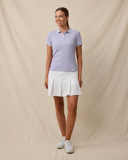 Model wearing the Sindy Rib Knit Polo in Cosmic Purple paired with a white golf skort