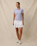 Model wearing the Sindy Rib Knit Polo in Cosmic Purple paired with a white golf skort