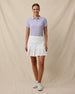 Full outfit view of the Sindy Rib Knit Polo in Cosmic Purple tucked into a white pleated golf skort