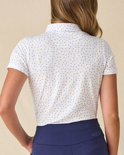 Women's Cherry Bloom Polo in White, back view on model featuring an allover purple and pink scattered floral print with Straight Down logo embroidered at center back neck, paired with navy pants