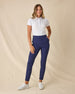 Women's Cherry Bloom Polo in White, full length front view on model featuring an allover purple and pink scattered floral print, paired with navy pants and white shoes