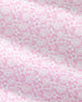 Pink and white tropical floral pattern with monstera leaves and small flowers, shown as a close-up fabric or wallpaper texture.