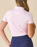Women's Kiana Polo in Pink Floyd, back view on model featuring a pink and white allover tropical floral and leaf print, paired with navy pants