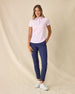 Women's Kiana Polo in Pink Floyd, full length front view on model featuring a pink and white allover tropical floral and leaf print, paired with navy pants and white shoes