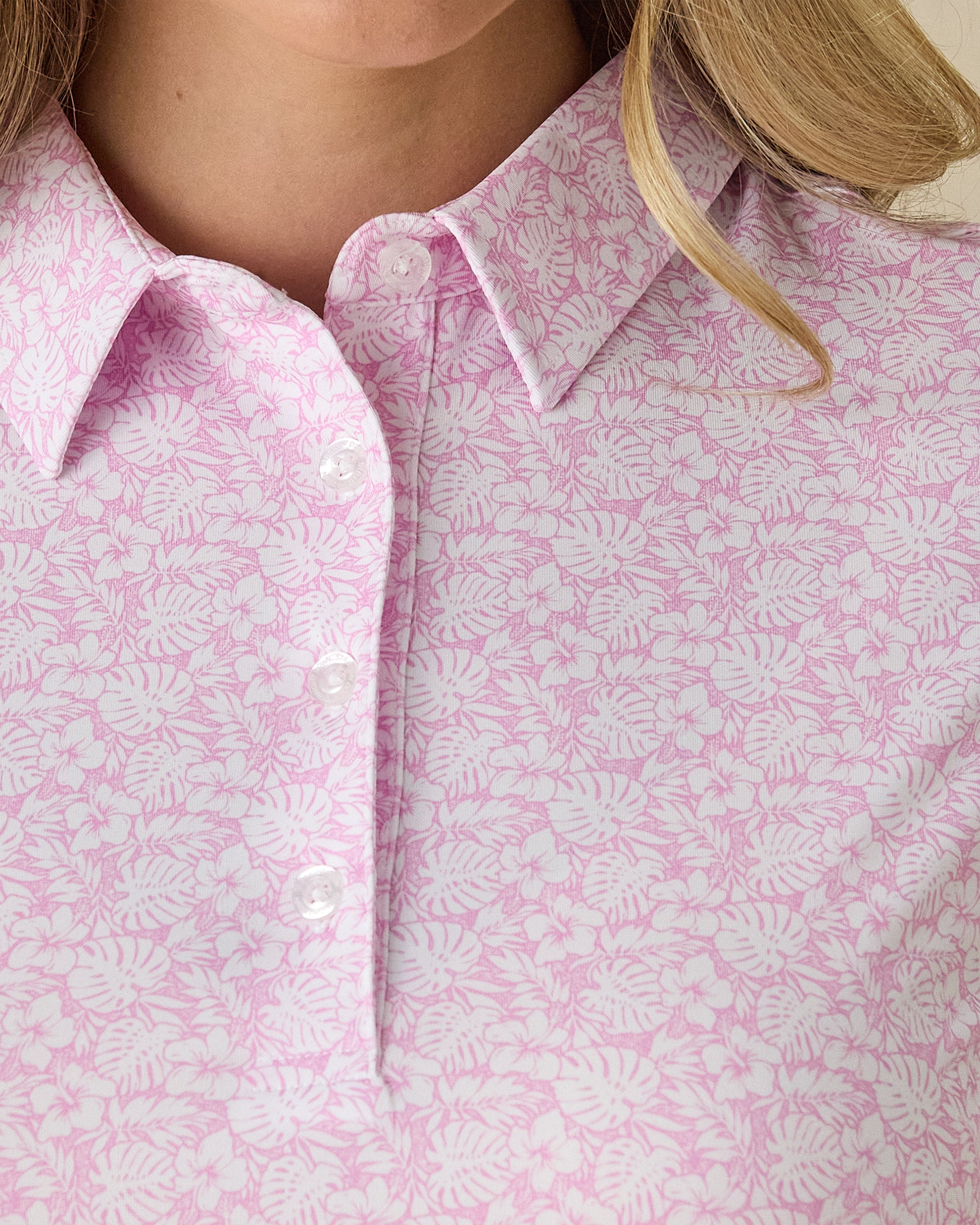 Women's Kiana Polo in Pink Floyd, close-up front view on model highlighting the pink and white allover tropical floral and leaf print
