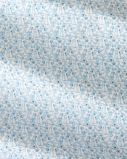 A close-up of a white fabric with a repeating light blue line-art pattern of small dogs in various poses.