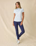 Dog Mom Polo in Coastal, full length front view worn by a model paired with navy ankle pants and white golf shoes, showcasing the light blue and white allover dog print pattern