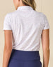 Women's Kokomo Polo in White, back view on model featuring an allover purple sketch-style tropical print with palm trees, florals, turtles, dolphins and pelicans, with tonal Straight Down logo embroidered at center back neck, paired with navy pants