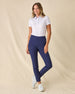 Women's Kokomo Polo in White, full length front view on model featuring an allover purple sketch-style tropical print with palm trees, florals, turtles, dolphins and pelicans, paired with navy pants and white shoes