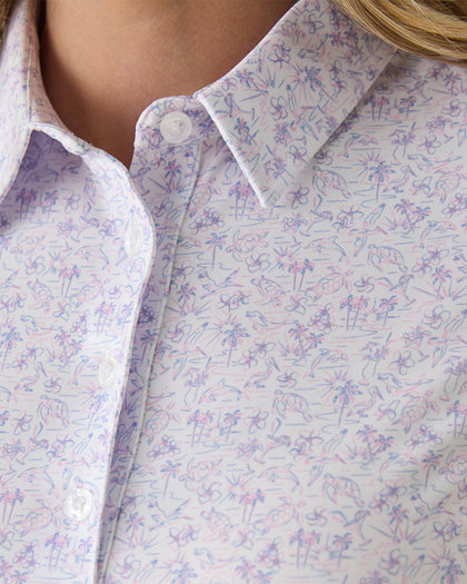 Women's Kokomo Polo in White, close-up front view on model highlighting the purple and pink sketch-style tropical print with palm trees, florals, turtles, dolphins and pelicans