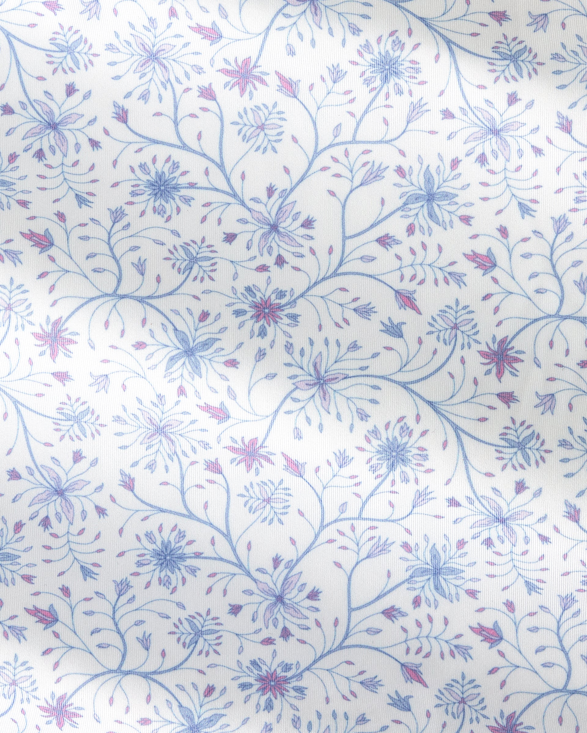 A close-up of a white fabric with a delicate, repeating floral pattern in light blue and dusty purple.