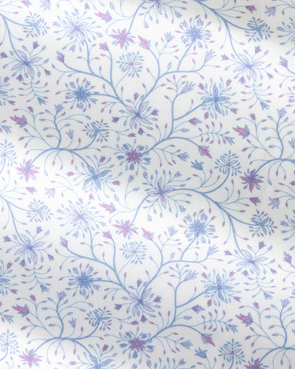 A close-up of a white fabric with a delicate, repeating floral pattern in light blue and dusty purple.
