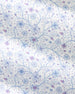 A close-up of a white fabric with a delicate, repeating floral pattern in light blue and dusty purple.