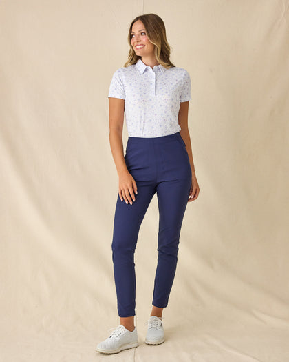 Women's Mariette Polo in Pink Floyd, full length front view on model featuring an allover blue and purple vine floral print, paired with navy pants and white shoes