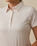 Close-up of the Huli Polo in Peach showing the pointed collar, button placket, short sleeve, and soft peach and white floral pattern.