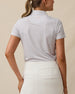 Back view of a woman wearing the Martini Girl Polo in Lemongrass with a white skort, featuring the allover martini glass print and embroidered logo below the back collar.