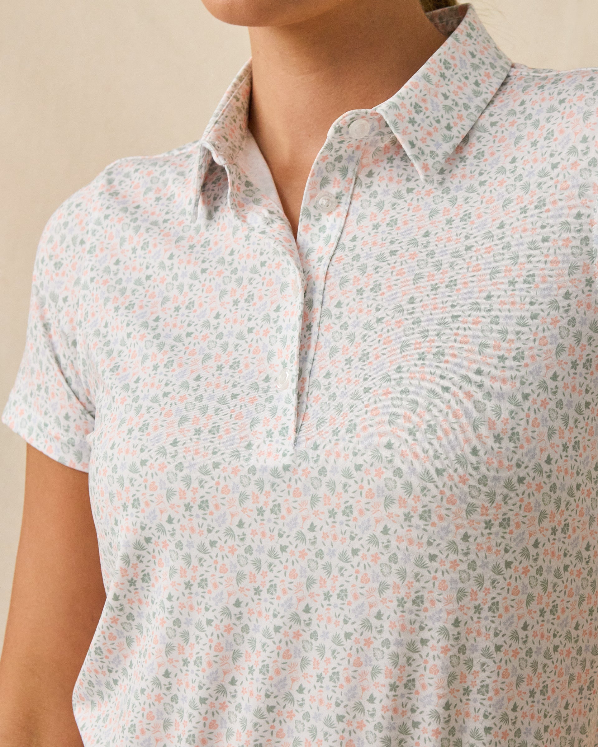 Close-up of the Palm Island Polo in Lemongrass showing the collar, button placket, and pastel tropical print.