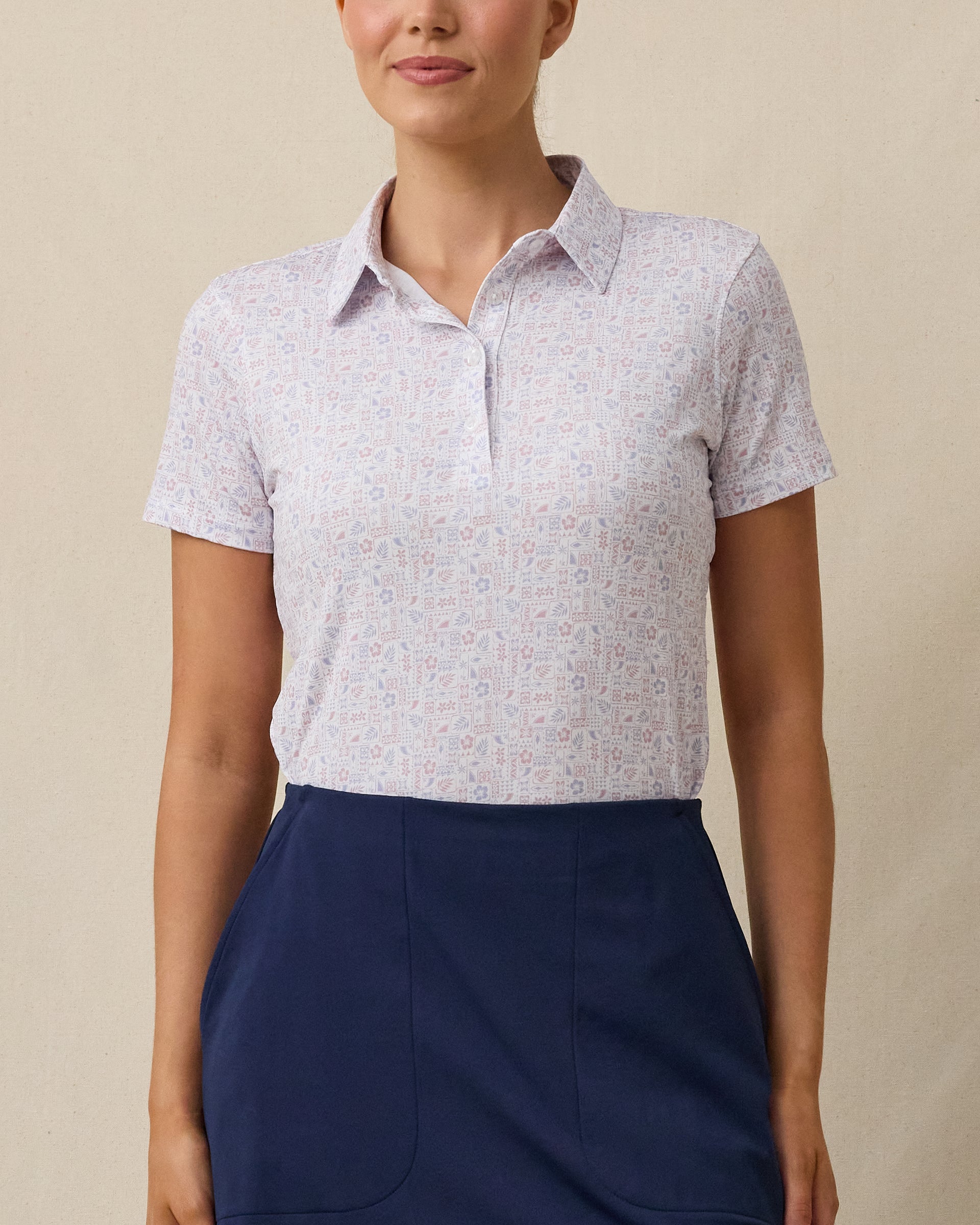 Model wearing the Lanakai Polo in Cosmic, featuring a white base with a pastel Hawaiian block-inspired print