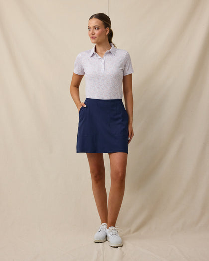 Model wearing the Lanakai Polo in Cosmic tucked into a navy golf skort