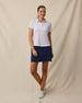 Model wearing the Lanakai Polo in Cosmic untucked with a navy golf skort