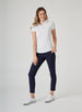 Women's Abbot Polo in White, full length side view on model featuring a white short-sleeve polo with spread collar and curved hem, paired with navy pants and white golf shoes