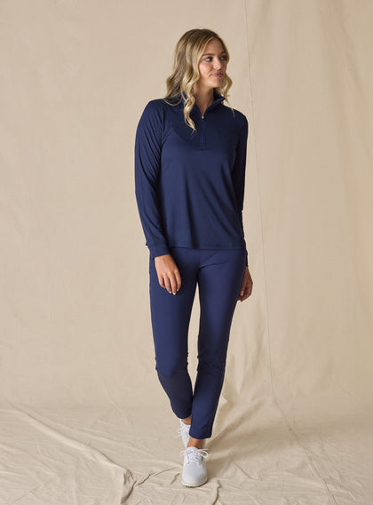 Women's Aero Quarter Zip in New Indigo, full body front view on model featuring a navy micro-texture long sleeve pullover with a quarter-zip neckline paired with navy pants and white golf shoes