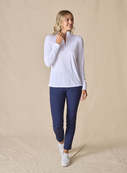 Women's Aero Quarter Zip in White, full-length front view on model featuring a clean white performance fabric with a quarter-zip neckline and long sleeves, paired with navy pants and white shoes
