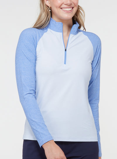 Woman wearing a light blue quarter-zip pullover with contrasting blue raglan sleeves, light body, and high collar
